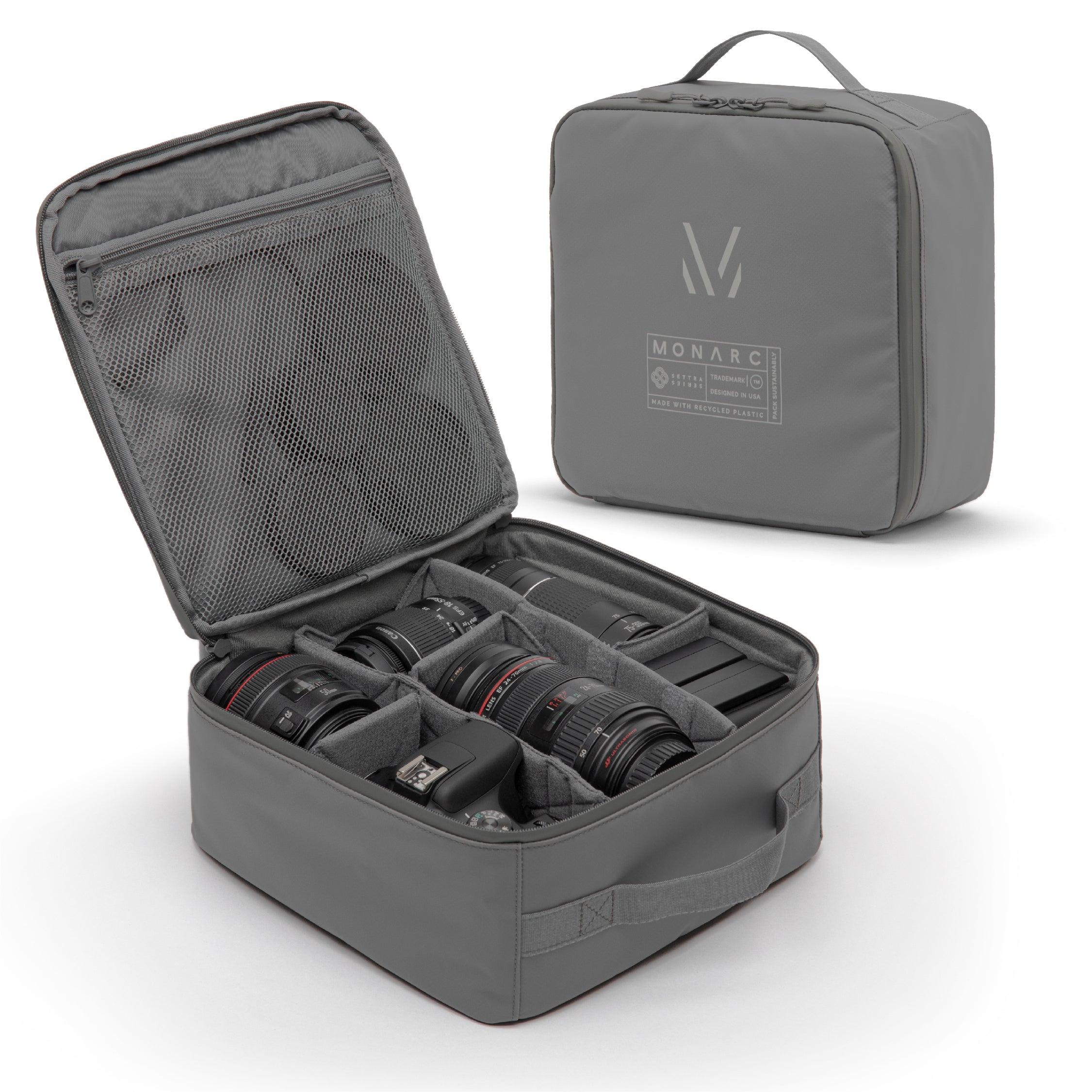 Monarc Camera Cube in gray, displayed open with various camera lenses and a camera body neatly organized inside. The cube's interior is designed for maximum protection with padded dividers, ensuring each piece of equipment is safely stored. The durable, water-resistant material provides further security for valuable photography gear.