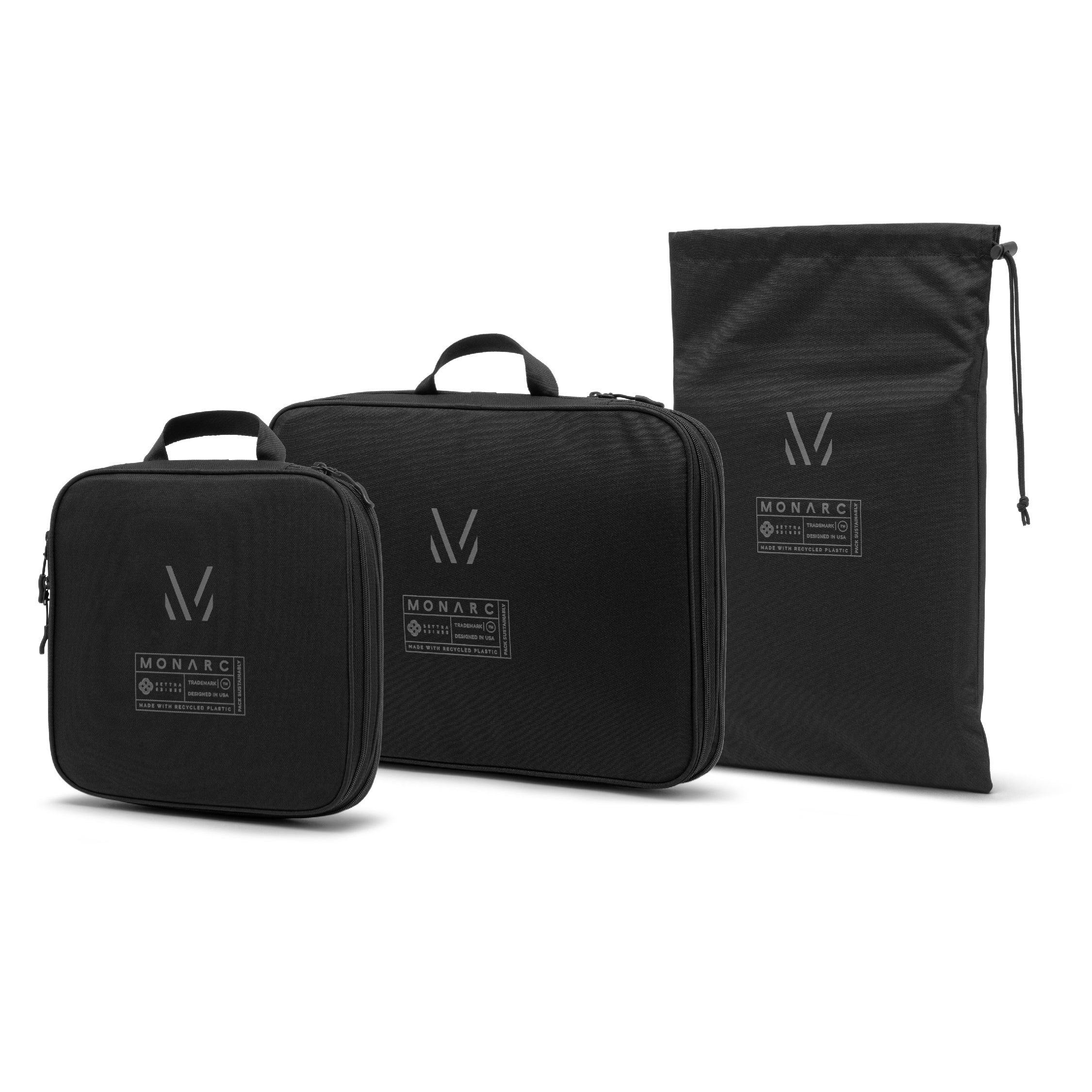 Monarc Travel Set featuring two black compression packing cubes and a sleek drawstring shoe bag, all adorned with the distinctive Monarc logo for a unified, stylish look designed for efficient packing and easy travel.