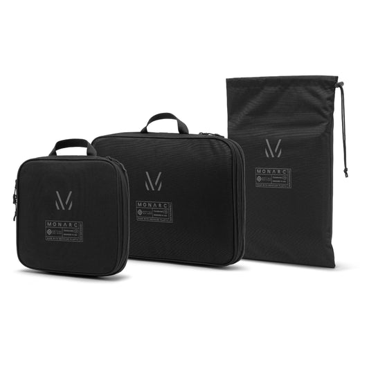 Monarc Travel Set featuring two black compression packing cubes and a sleek drawstring shoe bag, all adorned with the distinctive Monarc logo for a unified, stylish look designed for efficient packing and easy travel.